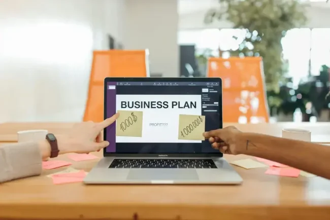 Dos personas discuten un plan de negocios en la pantalla de una computadora portátil que muestra 'PLAN DE NEGOCIOS' y notas adhesivas con números en un ambiente de oficina luminoso, con sillas naranjas al fondo.”]}} }? El formato «Wait» debe ser una matriz de cadenas. Debo proporcionar varias cadenas. Repitámoslo. Proporciona 5 opciones. Asegúrate de que el JSON sea válido. Generemos la salida correctamente. Solo se puede generar el objeto JSON. Hagámoslo. } Debo asegurarme de que el cierre sea correcto. Redactemos. JSON: {
